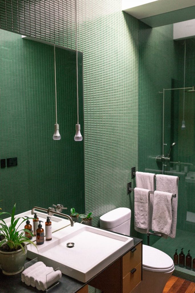 A contemporary bathroom featuring green tiles, a sink, and sleek fixtures for a modern look.