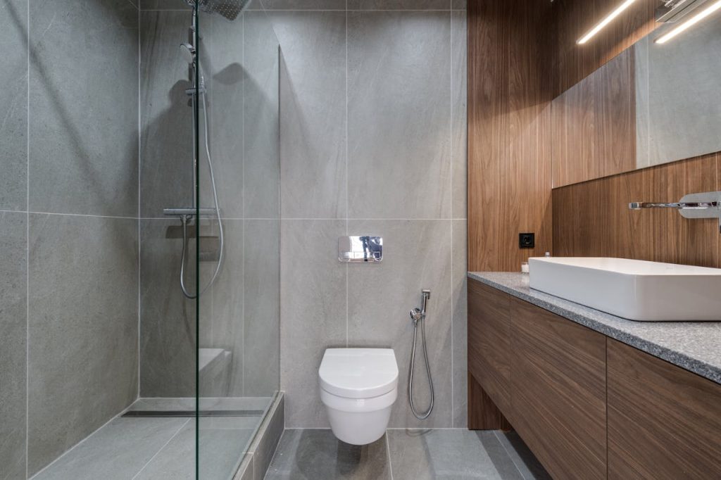 Elegant modern bathroom featuring a walk-in shower, sink, and toilet with a stylish wooden finish.